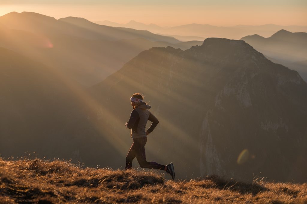 Kobieta biegająca w górach o zachodzie słońca.